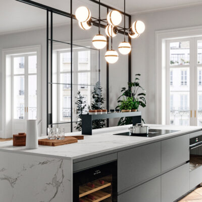 Cucina moderna con isola centrale in marmo, armadietti grigi e illuminazione elegante. Finestre ampie che offrono luce naturale.