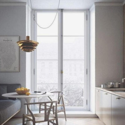 Cucina moderna con finestra che offre una vista invernale, tavolo rotondo e lampadario elegante. Elementi minimalisti e tonalità neutre.