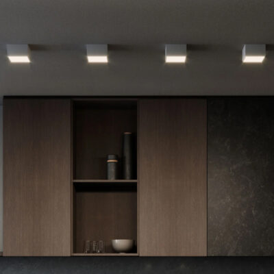 Illuminazione moderna su un mobile da cucina in legno scuro, con ripiani vuoti e decorazioni minimaliste.