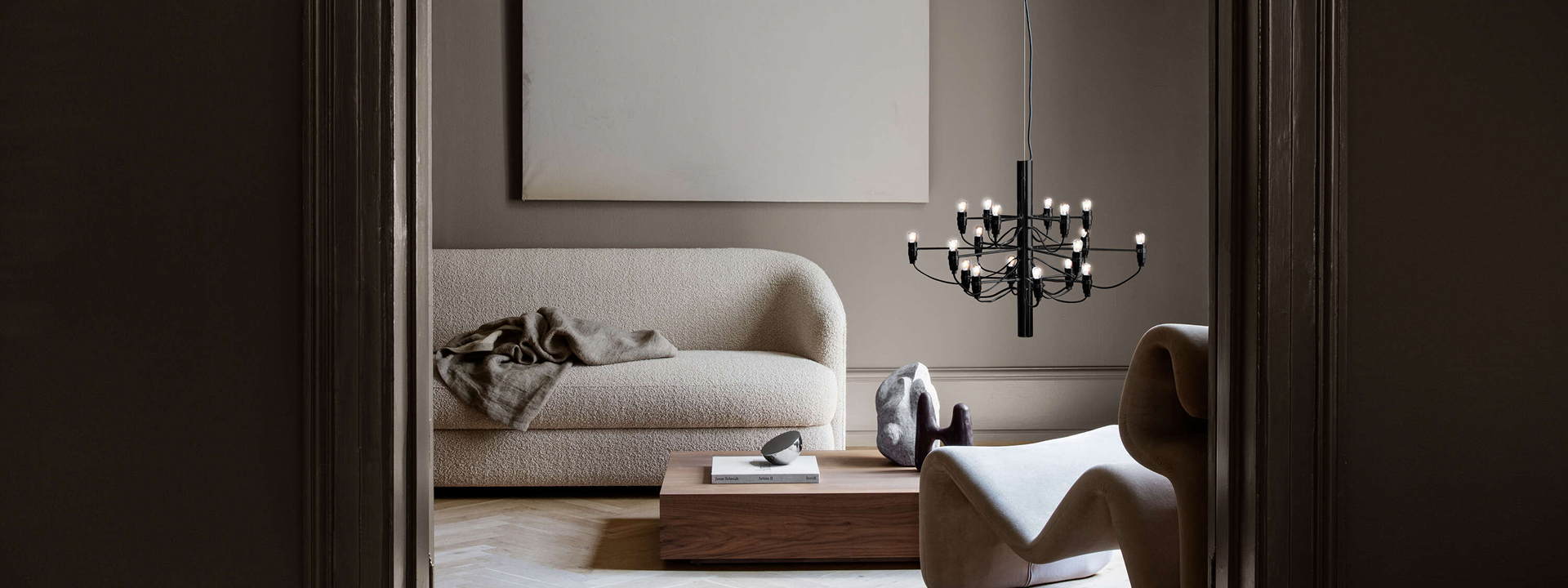 Un elegante soggiorno moderno con un divano beige, un tavolino in legno e un lampadario dal design minimalista. Dettagli di decorazione sofisticati.